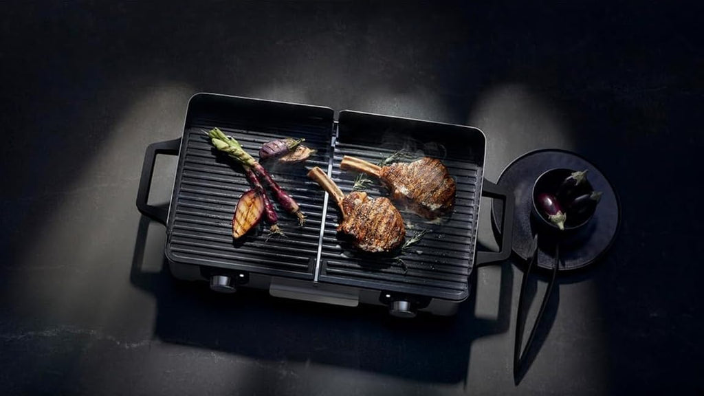 Parrilla eléctrica WMF Lono Master Grill 2026, 50x28 cm, parrilla de mesa eléctrica con paravientos y bandeja recogegrasa, certificada para uso exterior, 2 superficies de cocción ajustables independientemente, 2400 W, acero inoxidable mate.