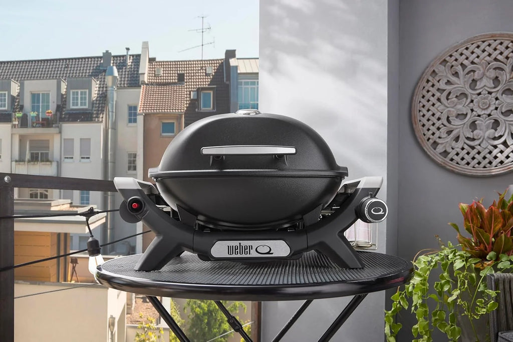 Parrilla de gas portátil Weber Q 1100N 2026, ligera, ideal para acampar, patios y balcones. Cuenta con quemador de alto rendimiento, rejillas de hierro fundido esmaltado y encendido electrónico. Color negro medianoche.