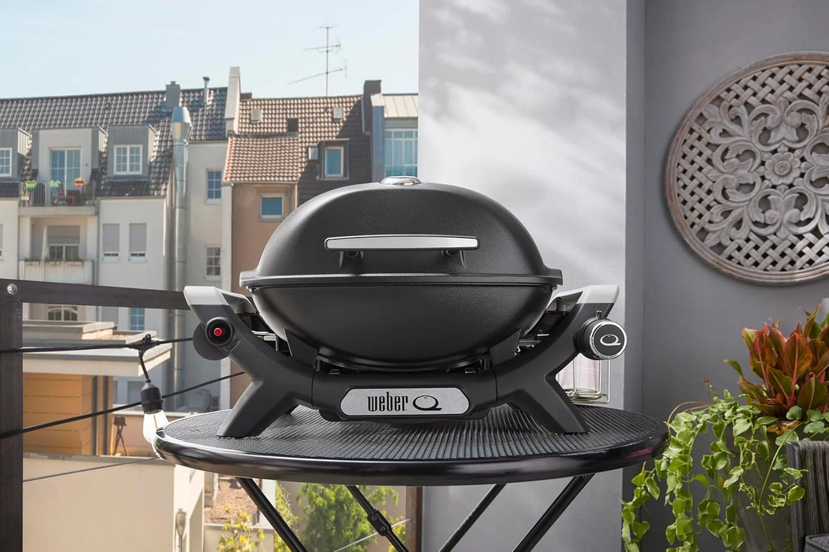 Parrilla de gas portátil Weber Q 1100N 2026, ligera, ideal para acampar, patios y balcones. Cuenta con quemador de alto rendimiento, rejillas de hierro fundido esmaltado y encendido electrónico. Color negro medianoche.